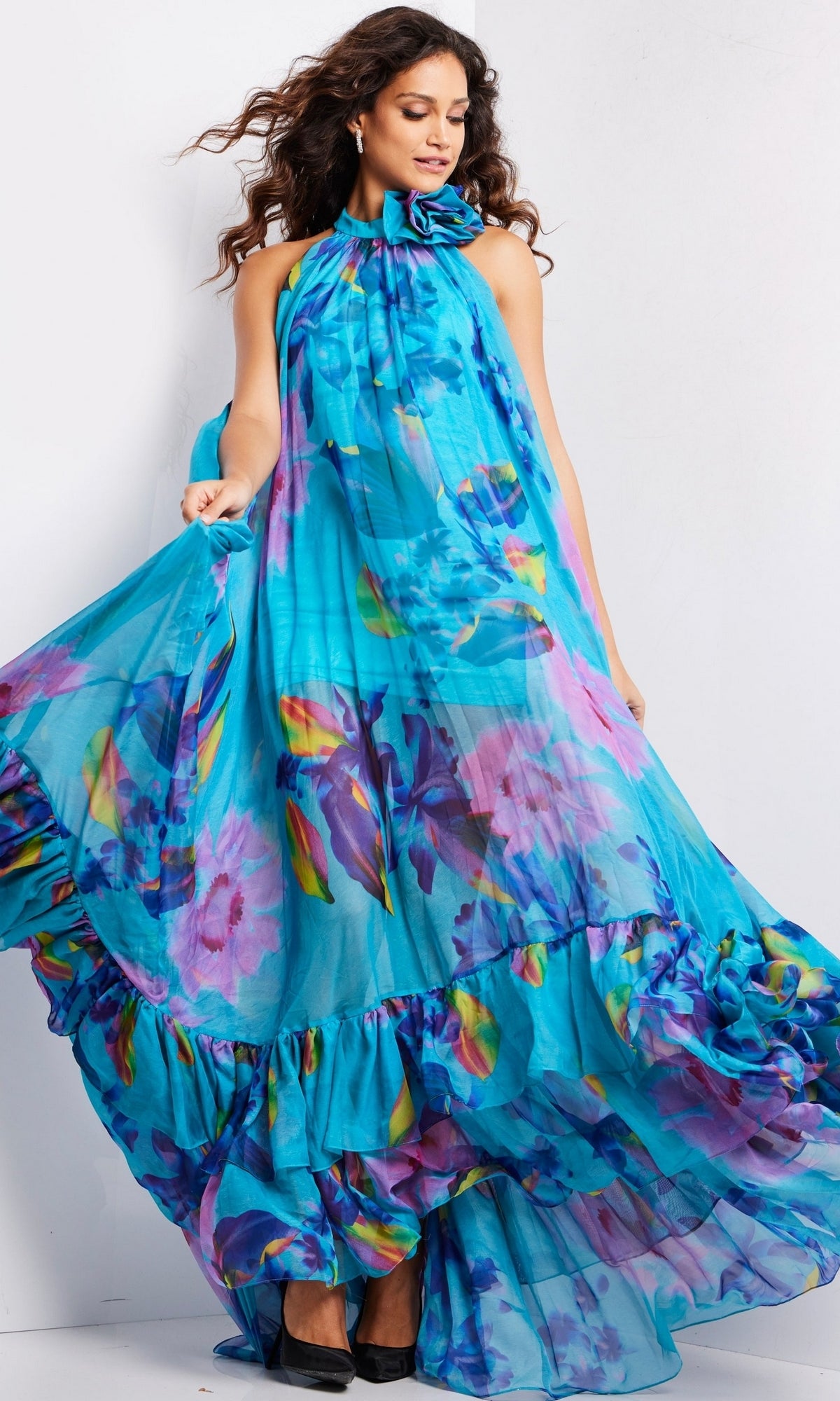 A woman wears the Long Prom Dress 38721 by Jovani, featuring blue ruffles, while standing against a plain white background.